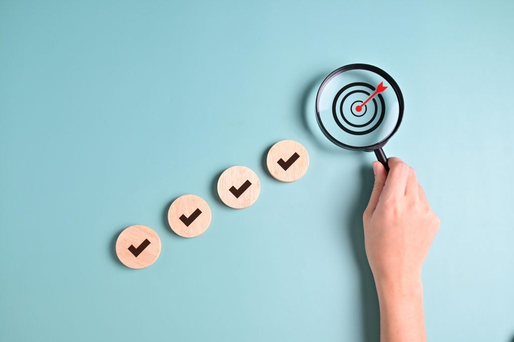 Eine Hand hält eine Lupe vor eine Zielscheibe - Da besonders professionals Auf LinkedIn unterwegs sind ist Linkedin Marketing durchaus teuer, dennoch kann sich der ROI rechnen