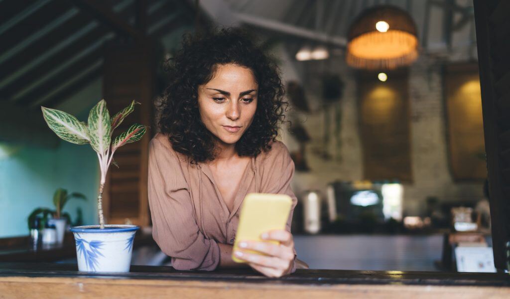 Eine Frau liest am Smartphone - Mit linkedin Marketing haben Sie die Möglichkeit, weltweit potenzielle Kunden und Mitarbeiter zu gewinnen.