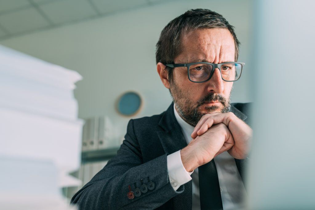 Verzweifelter Geschäftsmann blickt im Geschäftsbüro auf Laptopbildschirm -  Be- tobe Podcast Marketing erlaubt. Ihnen Fachwissen zu präsentieren und Glaubwürdigkeit und Vertrauen aufzubauen.