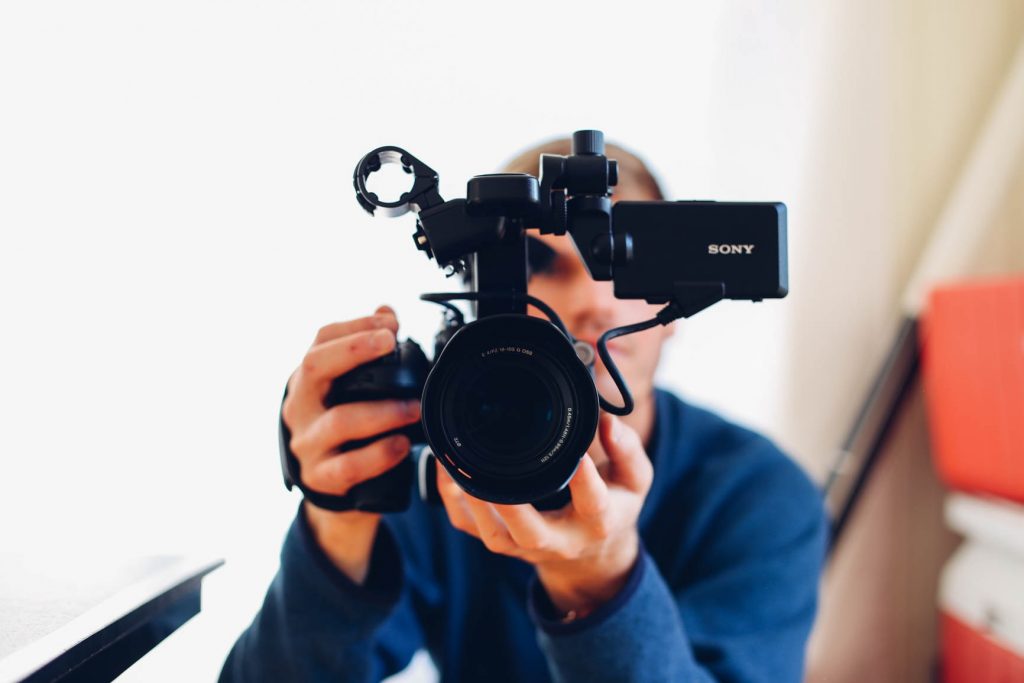 Ein Mann hält eine Kamera - Videomarketing lässt sich auch hervorragend im internen und externen Personalmarketing einsetzen