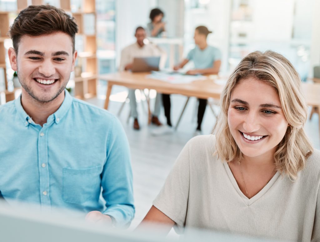Ein Mann Und eine Frau tauschen sich vor einem Laptop aus - Eine offene Kommunikation ist bei der Zusammenarbeit mit einer Marketing-Agentur wichtig.